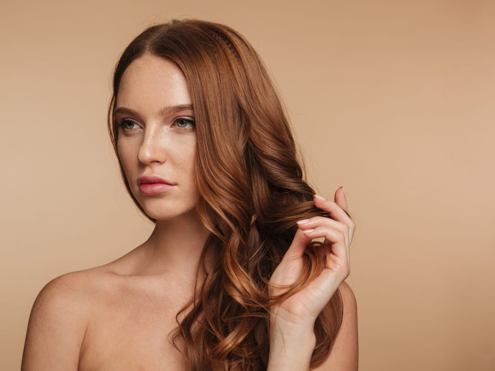 Beauty portrait of pretty ginger woman with long hair posing Beauty portrait of pretty ginger woman with long hair posing and looking away over cream background